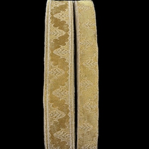 May include: Two gold-colored fabric trims with a repeating pattern of stylized leaves. The trims are approximately 1 inch wide and have a subtle sheen.