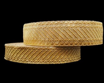 May include: Two rolls of gold-colored trim with a chevron pattern. The trim is made of a woven fabric with a subtle sheen.