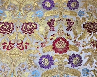Puede incluir: Primer plano de una tela decorativa con un patrón floral repetido. La tela presenta diseños florales dorados, burdeos, morados y azul claro sobre un fondo gris claro. El patrón incluye flores estilizadas, hojas y racimos de uvas.
