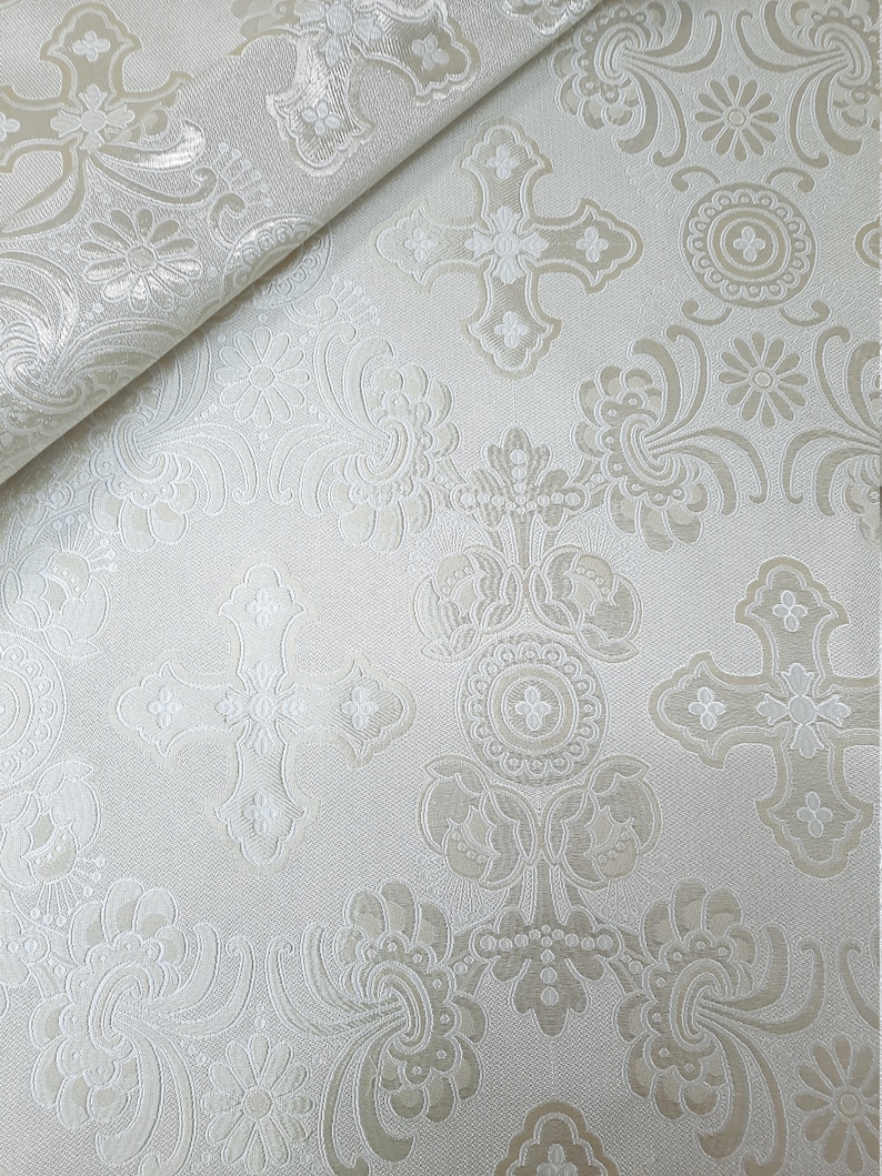 May include: White fabric with a raised embossed pattern of crosses and floral designs.