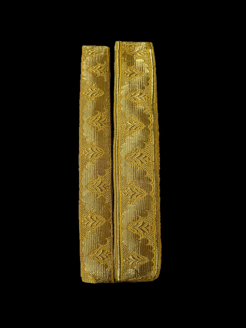 May include: Two gold-colored fabric trims with a repeating geometric pattern.