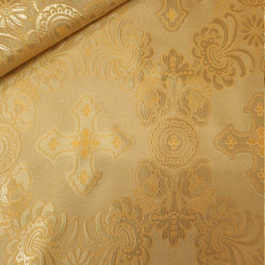 May include: Gold fabric with a repeating pattern of crosses and floral designs.