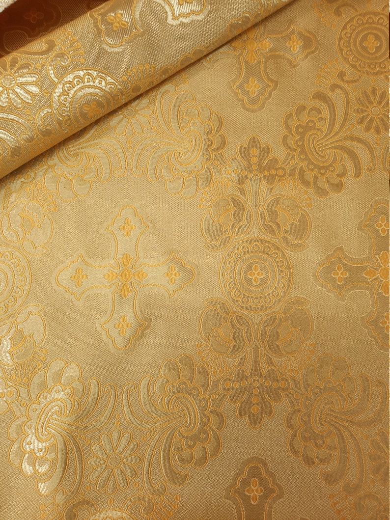May include: Gold fabric with a repeating pattern of crosses and floral designs.