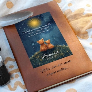 Può includere: Un diario rilegato in pelle marrone con un'immagine stampata di due orsacchiotti su una collina erbosa sotto un cielo stellato. L'immagine include testo in tedesco. Il diario riporta la scritta "Leonard 10.07.2025" e "Was ich dir noch sagen wollte..."
