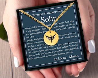 May include: A gold-colored necklace with a circular pendant featuring a black phoenix design. The pendant hangs from a delicate chain. The necklace is presented on a card with German text.