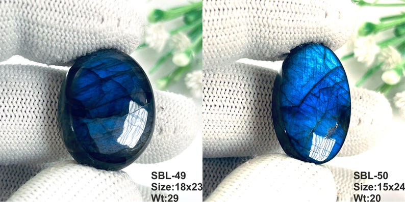 Pu&ograve; includere: Due pietre preziose di labradorite di forma ovale con un profondo riflesso blu iridescente. La pietra a sinistra &egrave; etichettata SBL-49, dimensioni 18x23, peso 29. La pietra a destra &egrave; etichettata SBL-50, dimensioni 15x24, peso 20. Superficie liscia.