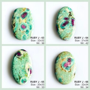 May include: Four oval-shaped polished gemstones featuring a mottled mint green and teal matrix with embedded deep magenta ruby inclusions. Each stone is labelled with text including RUBY J-63, 64, 65, 66, along with dimensions in mm and weight in carats.