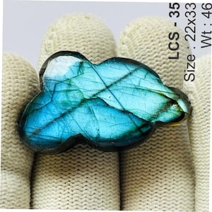 May include: A polished, cloud-shaped labradorite gemstone displaying vibrant blue and green iridescence with visible internal fractures. The stone is labelled LCS-35, with a size of 22x33 and a weight of 46, printed clearly on the side of the image.