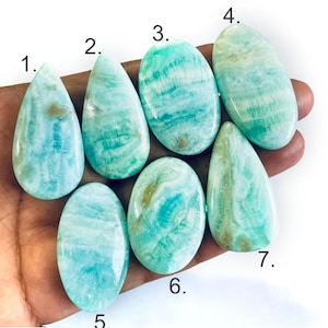Peut inclure: Sept cabochons polis, lisses, aux motifs turquoise et blancs, num&eacute;rot&eacute;s de un &agrave; sept. Ces pierres pr&eacute;sentent des textures marbr&eacute;es et tourbillonnantes dans des tons bleu clair, sarcelle et cr&egrave;me, avec des formes ovales et en goutte.