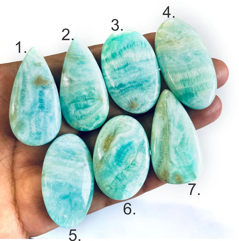 Peut inclure: Sept cabochons polis, lisses, aux motifs turquoise et blancs, num&eacute;rot&eacute;s de un &agrave; sept. Ces pierres pr&eacute;sentent des textures marbr&eacute;es et tourbillonnantes dans des tons bleu clair, sarcelle et cr&egrave;me, avec des formes ovales et en goutte.