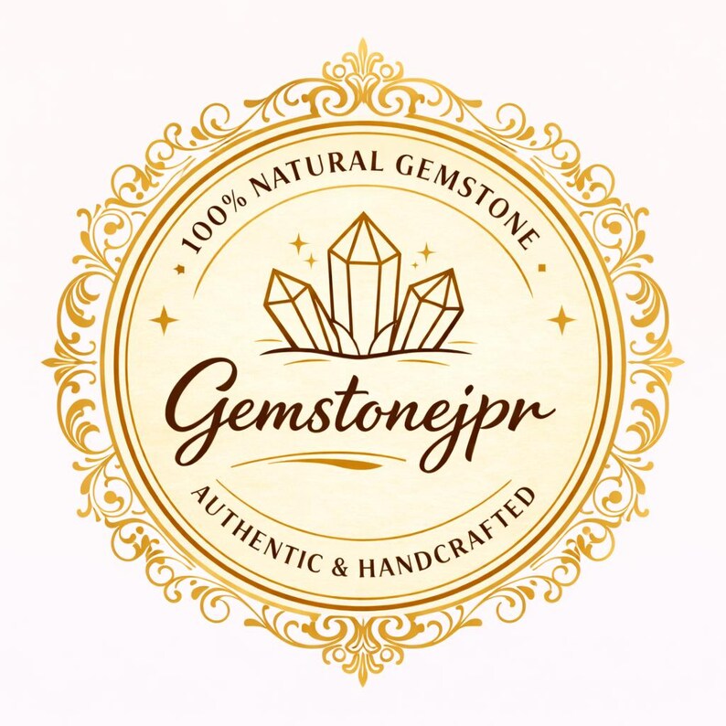 May include: A gold-colored circular logo with the text "100% NATURAL GEMSTONE" and "Gemstonejpr AUTHENTIC & HANDCRAFTED". The logo features a stylized illustration of three crystals and decorative flourishes.