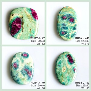 May include: Four polished cabochon gemstones featuring a mix of vibrant magenta ruby inclusions within a matrix of green and cream-coloured zoisite. Each stone is labelled with a code, dimensions in millimetres, and weight in carats: RUBY J-47 (30x33mm, 62ct), RUBY J-48 (26x43mm, 73ct), RUBY J-49 (29x40mm, 86ct), and RUBY J-50 (26x40mm, 53ct).