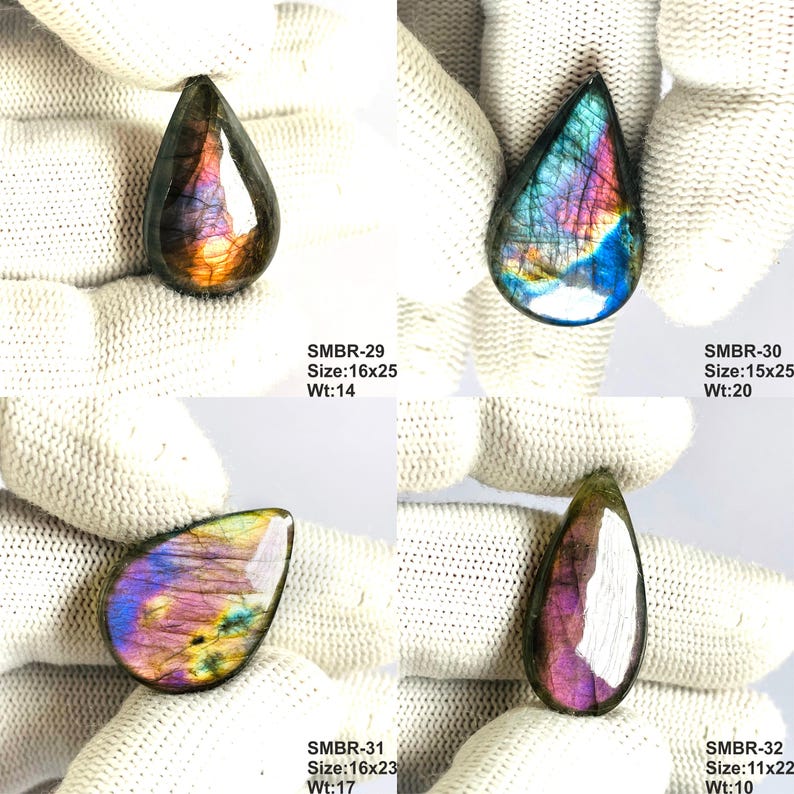May include: Four teardrop-shaped labradorite gemstones with iridescent colors of blue, purple, and gold. Each stone is held against a white background. The sizes range from 0.43 x 0.87 inches to 0.63 x 0.98 inches.