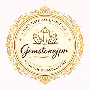 K&ouml;nnte beinhalten: Goldfarbenes kreisf&ouml;rmiges Logo mit dem Text "100% NATURAL GEMSTONE" und "Gemstonejpr AUTHENTIC & HANDCRAFTED". Das Logo zeigt eine stilisierte Illustration von drei Kristallen und dekorativen Verzierungen.