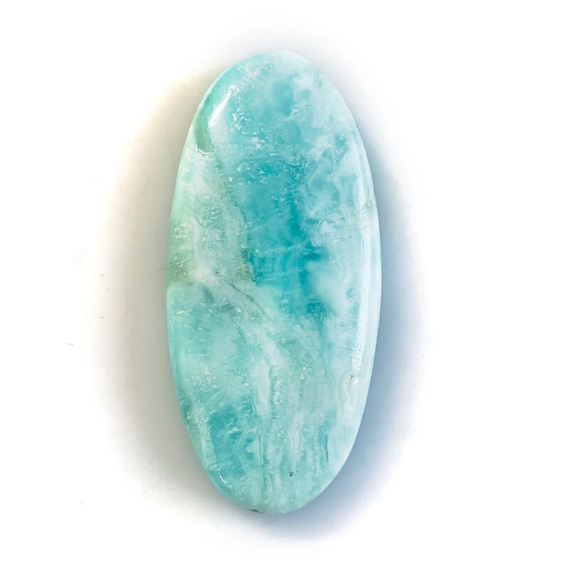 Peut inclure: Un cabochon de pierre pr&eacute;cieuse de forme ovale pr&eacute;sentant une surface polie avec des motifs tourbillonnants de bleu clair, de turquoise et de blanc. La pierre a une texture lisse et arrondie avec une finition brillante et lustr&eacute;e.