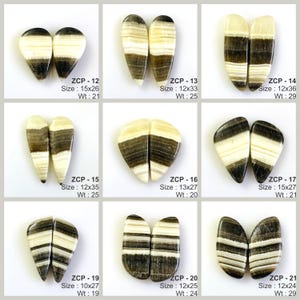 May include: A collection of nine pairs of polished gemstones, each with a unique shape and pattern. The stones feature a mix of cream, brown, and black bands. Each pair is labeled with a code, size in millimeters, and weight in grams.
