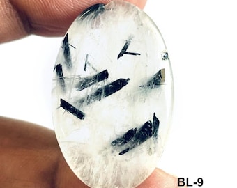 Peut inclure: Une pierre précieuse de quartz clair de forme ovale présentant des inclusions distinctes d'aiguilles de tourmaline noire. Le texte BL-9, Size: 22x36, Wt: 41 est imprimé dans le coin inférieur droit de l'image.
