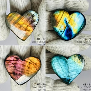 May include: Four heart-shaped labradorite stones with iridescent surfaces. Top left HS-77 measures 28x28mm, weight 46g. Top right HS-78 measures 28x32mm, weight 55g. Bottom left HS-79 measures 28x32mm, weight 53g. Bottom right HS-81 measures 26x30mm, weight 31g.