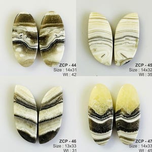 May include: Four pairs of polished gemstone cabochons. Each pair has a unique pattern of beige, brown, and black swirls. The text on the image indicates sizes ranging from 13x33 mm to 14x33 mm.