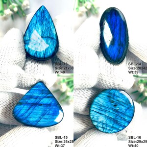 Pu&ograve; includere: Quattro pietre preziose di labradorite lucida con vibrante iridescenza blu. SBL-13 misura 21x38mm, 40ct; SBL-14 misura 20x42mm, 39ct; SBL-15 misura 26x28mm, 37ct; SBL-16 misura 29x29mm, 40ct. Ogni pietra mostra fratture e luce blu profonda.