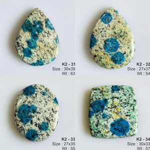 May include: Four K2 granite cabochons with blue azurite spots. K2-31 is a 30x39mm teardrop. K2-32 is a 27x37mm teardrop. K2-33 is a 27x35mm oval. K2-34 is a 30x33mm square. Each stone features a speckled white, gray, and black granite base.