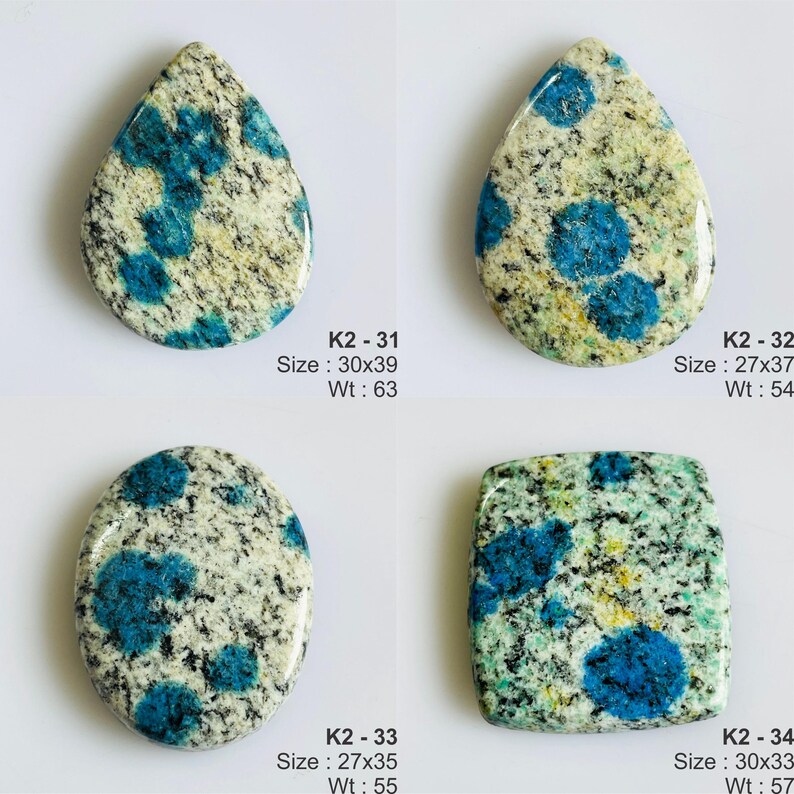 May include: Four K2 granite cabochons with blue azurite spots. K2-31 is a 30x39mm teardrop. K2-32 is a 27x37mm teardrop. K2-33 is a 27x35mm oval. K2-34 is a 30x33mm square. Each stone features a speckled white, gray, and black granite base.