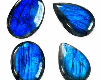 May include: Four polished labradorite gemstones arranged in a grid. Two stones are oval-shaped and two are teardrop-shaped. Each stone displays a vibrant, iridescent blue flash across its surface with visible internal fractures and dark edges.
