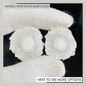 May include: Two natural white solar quartz slices with a circular, radiating crystalline structure. The stones feature a translucent, milky white center surrounded by jagged, textured edges. Text on the image reads: NATURAL WHITE SOLAR QUARTZ SLICE and NEXT TO SEE MORE OPTIONS.