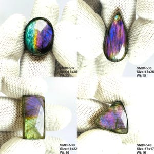 May include: Four polished labradorite gemstones in various shapes: oval, teardrop, rectangular, and triangular. The stones display iridescent colors of blue, purple, and green. The oval stone is 15x20 mm and weighs 22. The teardrop is 13x26 mm and weighs 15.