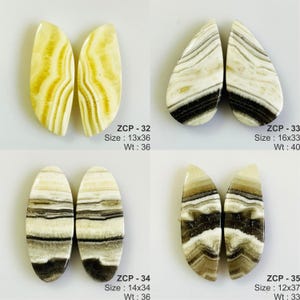May include: Four pairs of polished gemstone cabochons in various shapes. The stones feature a mix of cream, brown, and black banding. The text on the image indicates sizes ranging from 12x37 to 16x33, and weights from 33 to 40.