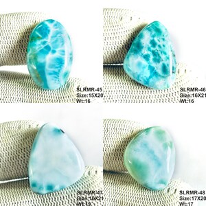 May include: Four polished larimar gemstones with blue and white marbled patterns. Each stone is labeled with codes and dimensions in mm: SLRMR-45 15x20, SLRMR-46 16x21, SLRMR-47 16x21, and SLRMR-48 17x20. The stones display varied cloud-like textures and hues.