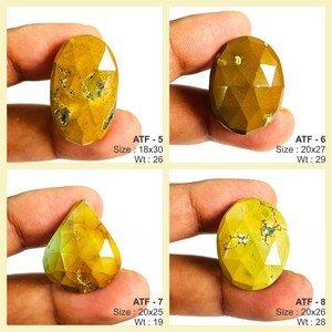 May include: Four faceted, yellow-brown gemstones with varying shapes are displayed. Each stone is held in a hand, showcasing the unique cuts and natural patterns. The sizes range from 18x30 to 20x27, with weights from 19 to 29. The text "ATF" and size/weight details are visible.