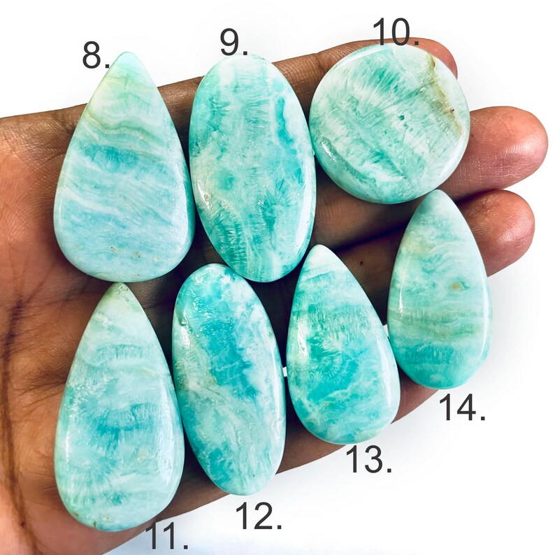 Peut inclure: Sept cabochons polis, lisses, aux motifs bleu clair et blanc, de formes vari&eacute;es, notamment en goutte, ovale et ronde, &eacute;tiquet&eacute;s avec les num&eacute;ros 8 &agrave; 14, pr&eacute;sentant des veines min&eacute;rales naturelles et une finition de surface brillante.