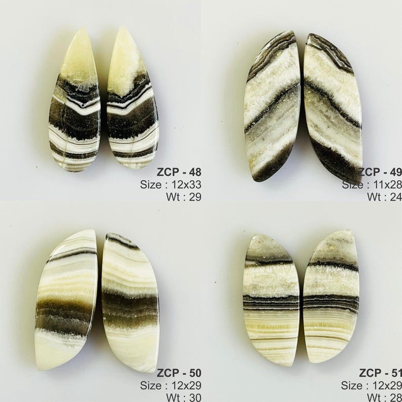 May include: Four pairs of polished onyx stones in teardrop and oval shapes. The stones feature cream, black, and brown banding. Each pair is labeled with a size in millimeters and weight in grams. The text "ZCP" is also visible.