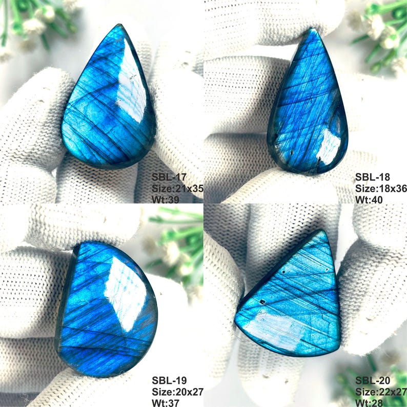 Pu&ograve; includere: Quattro pietre preziose di labradorite lucida con iridescenza blu. SBL-17 misura 21x35mm a 39ct, SBL-18 18x36mm a 40ct, SBL-19 20x27mm a 37ct e SBL-20 22x27mm a 28ct. Ogni pietra mostra una forma distinta e un profondo riflesso blu.