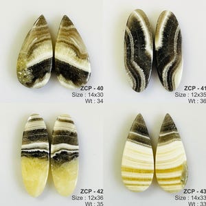 May include: Four pairs of polished gemstone cabochons. Each pair has a unique pattern of brown, white, and black swirls. The shapes include teardrop and oval. The text on the image indicates sizes and weights.