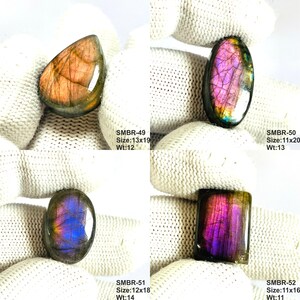 May include: Four polished labradorite gemstones in various shapes: teardrop, oval, and rectangular. The stones display iridescent flashes of purple, pink, and gold. Each stone has a size and weight listed: SMBR-49, SMBR-50, SMBR-51, and SMBR-52.