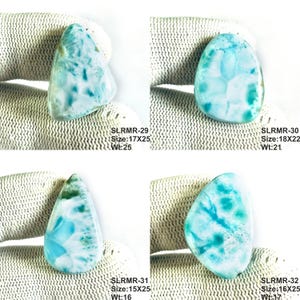 May include: Four polished larimar gemstones with blue and white patterns. Each stone is labeled with text: SLRMR-29 Size:17X25 Wt:25, SLRMR-30 Size:18X22 Wt:21, SLRMR-31 Size:15X25 Wt:16, and SLRMR-32 Size:16X25 Wt:17, indicating specific dimensions.