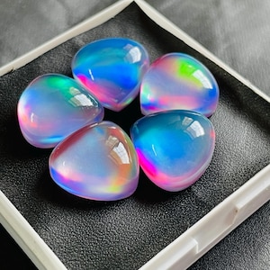 May include: Five iridescent heart-shaped cabochons in shades of blue, pink, and green. The cabochons are displayed in a white box with a black interior.