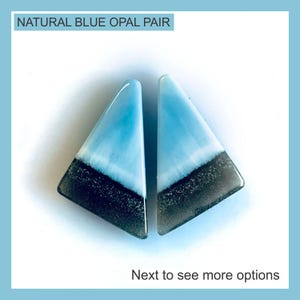 Puede incluir: Un par de piedras preciosas de ópalo azul natural de forma triangular con una superficie lisa y pulida. Cada piedra muestra un degradado de color distintivo, pasando de un azul cielo claro en la parte superior a una base gris carbón oscura. Texto: NATURAL BLUE OPAL PAIR.