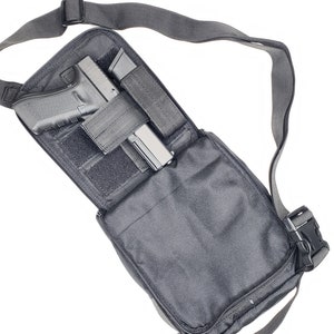May include: Black tactical shoulder bag with a black handgun and magazine inside. The bag has a zippered closure and an adjustable shoulder strap.