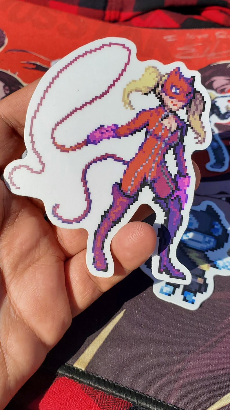 Pode incluir: Um adesivo de pixel art de uma personagem feminina em um macac&atilde;o vermelho com um chicote. Ela tem cabelo loiro e uma m&aacute;scara vermelha. O adesivo est&aacute; em um fundo branco.