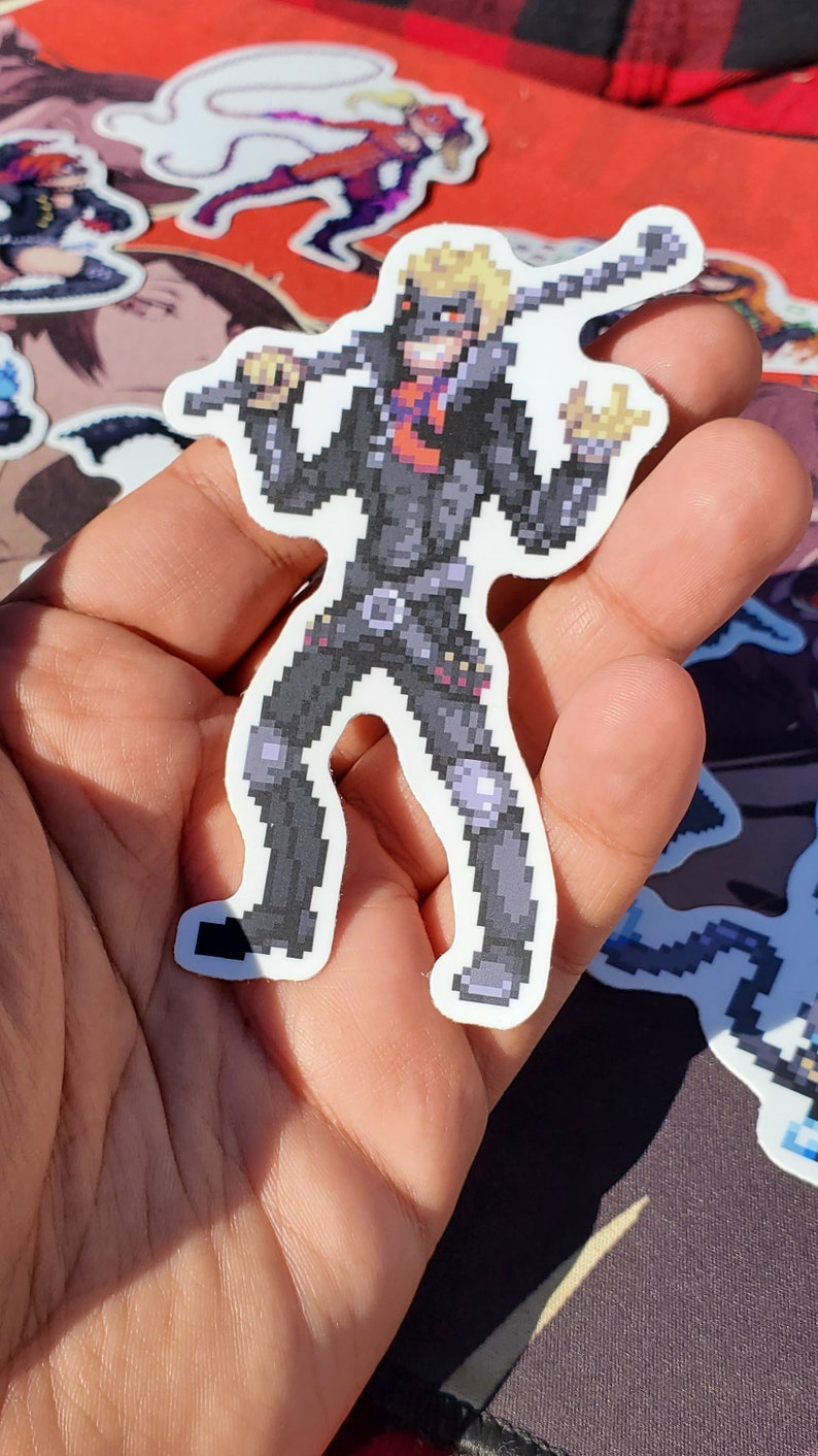 Pode incluir: Um adesivo de pixel art de um personagem vestindo uma jaqueta de couro preta, cal&ccedil;as pretas e uma m&aacute;scara preta. O personagem est&aacute; segurando uma arma e tem uma express&atilde;o determinada no rosto.