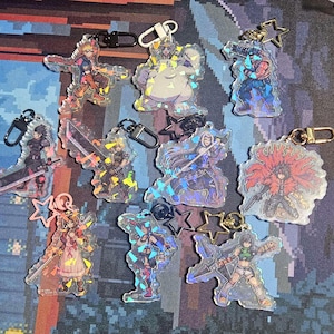 May include: A set of ten holographic character charms featuring various characters from the Final Fantasy video game series. The charms are made of clear plastic with a holographic finish and feature different characters from the Final Fantasy series, including Cloud Strife, Sephiroth, Tifa Lockhart, Aerith Gainsborough, and Yuffie Kisaragi.