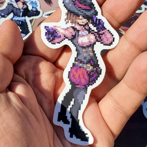 Pode incluir: Um adesivo de pixel art de uma personagem feminina vestindo uma roupa roxa e preta com um chap&eacute;u. A personagem est&aacute; segurando uma arma e tem uma express&atilde;o determinada no rosto.