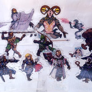Może przedstawiać: Kolekcja jedenastu przezroczystych akrylowych podstawek z postaciami w stylu pixel art w strojach fantasy, w tym wojownicy w zbrojach z bronią, rogata istota, mag z księgą oraz postać w fioletowej szacie trzymająca kostur.