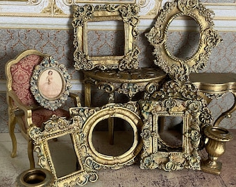 May include: A collection of ornate gold-toned picture frames of various sizes and shapes, including a round frame, a square frame, and an oval frame. The frames are arranged on a table with a gold-toned base.