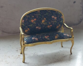 May include: A small, gold-painted, floral patterned,  upholstered settee with a curved back and ornate legs.