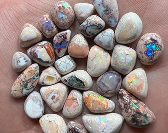 May include: A collection of 25 small, natural, white, brown, and iridescent opal stones. The stones are irregularly shaped and have a variety of patterns and colours.