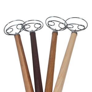 Puede incluir: Cuatro batidores de masa de acero inoxidable con mangos de madera. Los mangos varían en color, incluyendo marrón claro, medio y oscuro. Las cabezas de los batidores son de alambre de acero inoxidable en bucle.